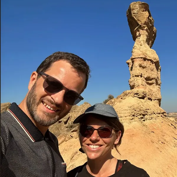 Claire and Fred, smiling, below a rock chimney in the Monegros desert, Aragon