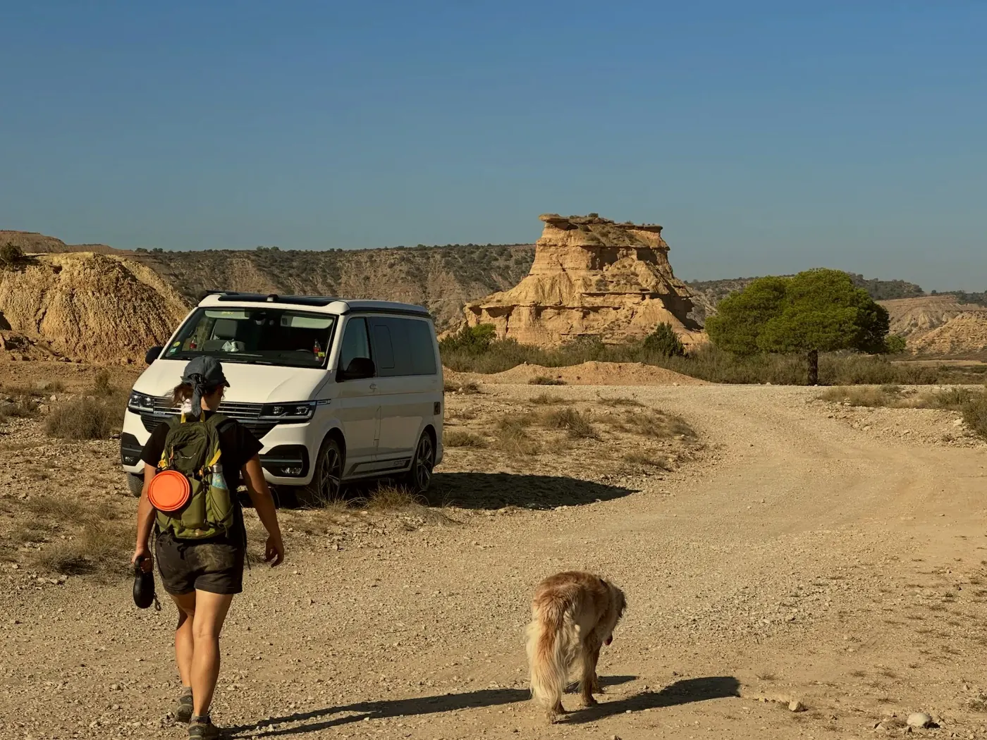 Claire and our dog walking towards our white van on a track in the Monegros desert, Aragon