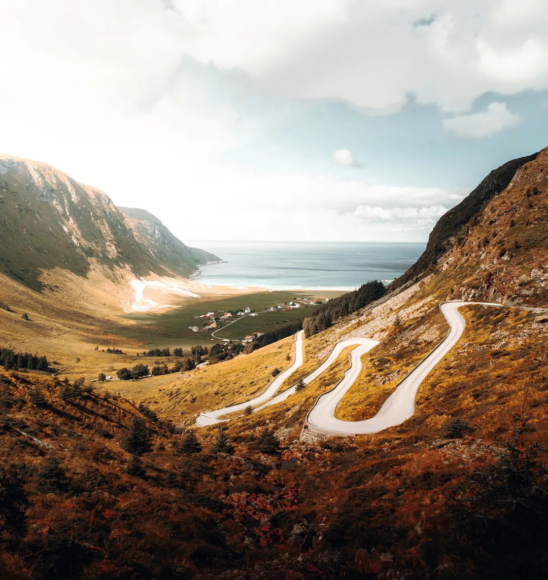 A mountain road winding in hairpins above a fjord